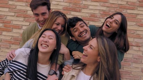 Six Friends Laughing Together in Front of a Brick Wall