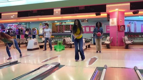 Freunde spielen Bowling und feiern Strike in Zeitlupe
