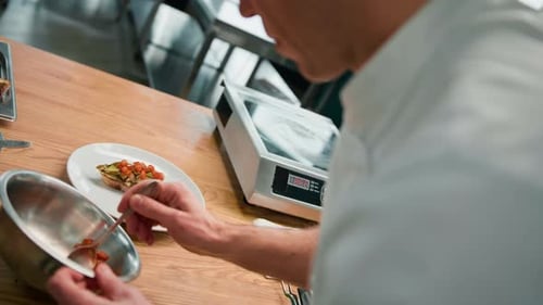 Professional chef puts avocado and tomato on toast with spices pouring sauce over it concept of food