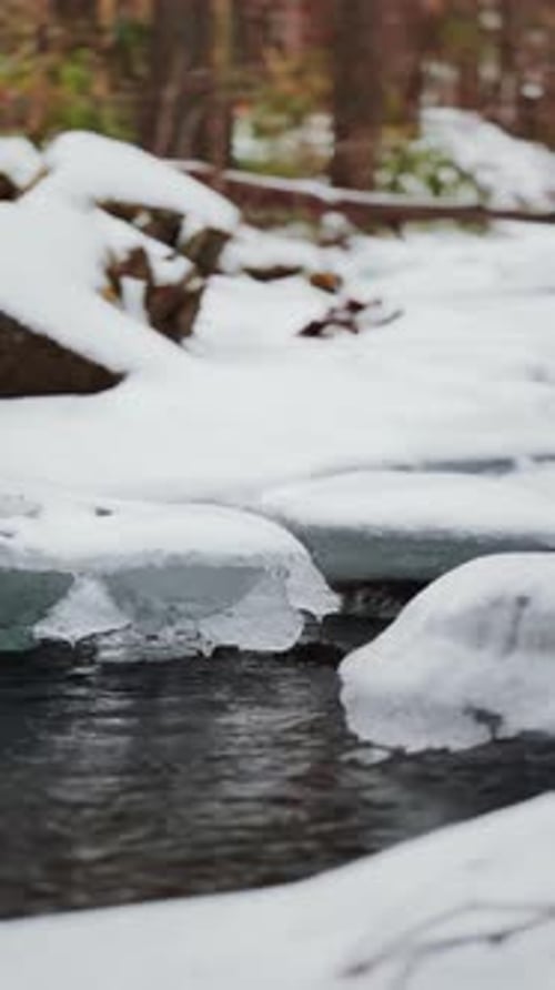 Icy winter stream flowing through snowy landscape