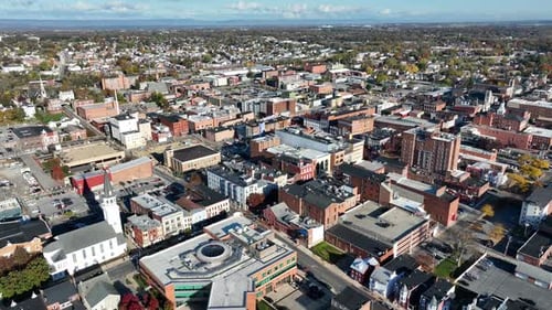 Aerial view of a dense, historic downtown area with distinct red and white church spire. High drone