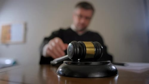 Mano de juez con mazo de madera y bandera estadounidense sobre fondo, primer plano del juez Gavel