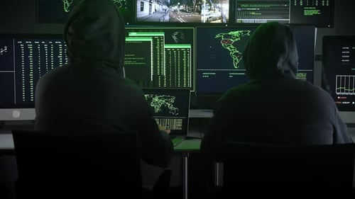 Hooded Figures in Dark Room with Computer Screens
