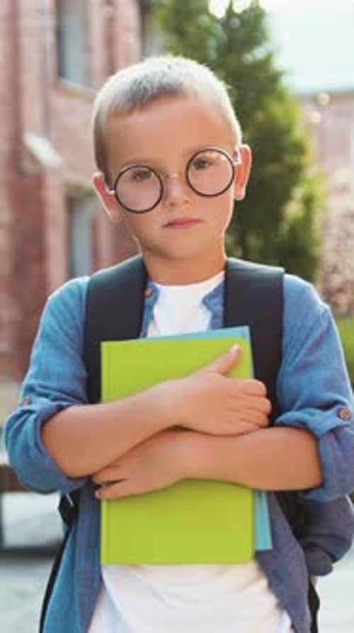 Portrait Little Boy Holding Books Standing Outside Near School Looking at Camera and Smiling Joyful