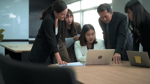 Group of business people looking at computer and discussing in modern office