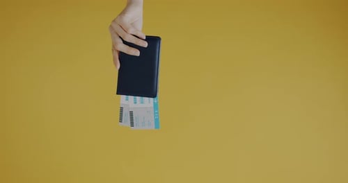 Closeup of Female Hand Holding Document and Tickets and Playing with Toy Plane on Yellow Color