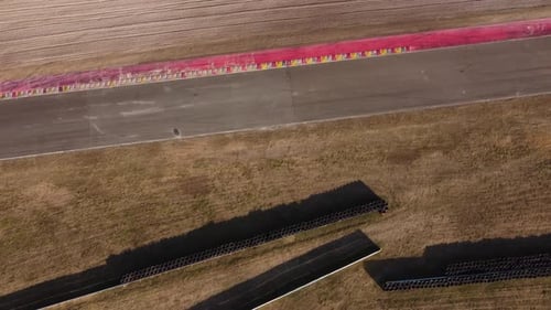 Aerial flyover racetrack and old vintage race car passing by during sunlight