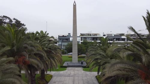 Vidéo 4K d'un Drone décollant et montant en altitude dans un parc avec un grand obélisque, et une carte