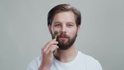 Bearded Man Using Jade Facial Roller for Skincare