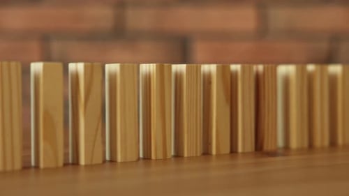 Risiko. Holzklötze, die im Dominoeffekt auf den Schreibtisch fallen, Nahaufnahme