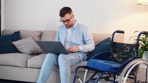 Young Man Using Laptop on Couch at Home