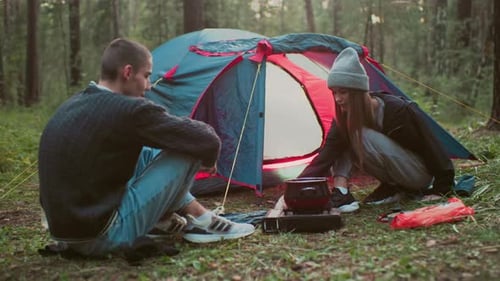 Young Couple Cooking Outside Tent During Camping in Forest
