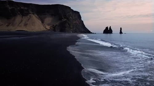 Aerial view of the black sand beach of Reynisfjara, Iceland. Drone moving along the beach with cliff