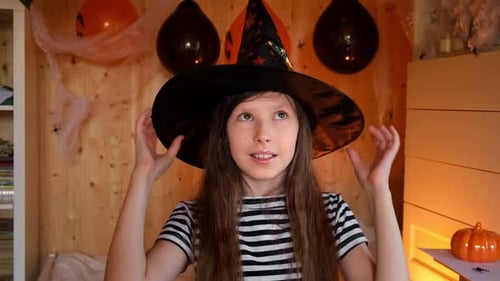 Girl in Witch Hat Smiling in Decorated Room