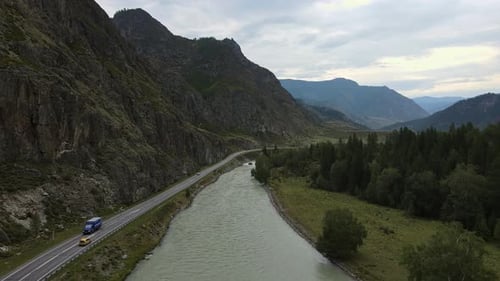 Aerial View of a Valley with a Winding River and Road Surrounded By Mountains