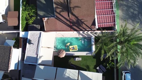 Friends at swimming pool aerial drone view of people that swim at pool floating over inflatable bed