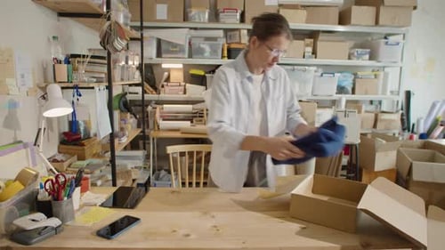 Woman Packing Clothes into Parcel Box in Online Store Warehouse