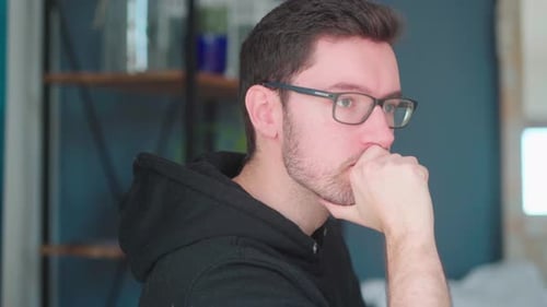 Pensive young man sitting pondering in living room. deep thought considering problems solving, havin