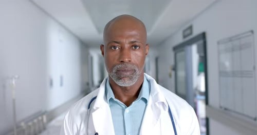 Portrait of african american male doctor wearing lab coat and stethoscope at hospital, slow motion