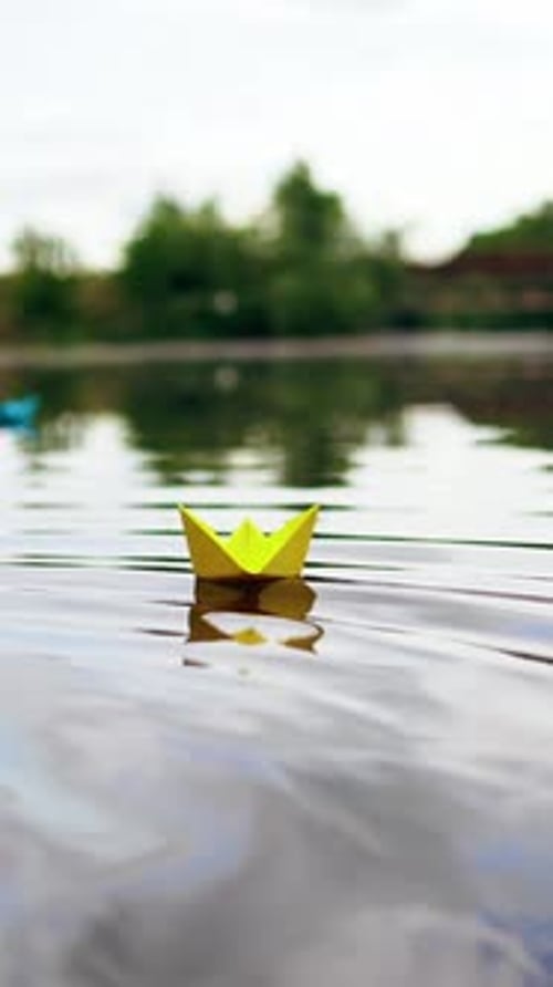 A paper ship floating in the river on the waves. Origami Paper Boat. Vertical video