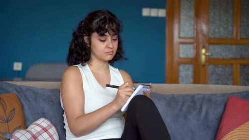 Young Woman Writing in Notebook on Couch