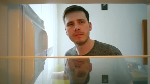 Man Looking Inside Empty Refrigerator