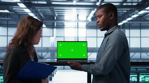 Technicians in Data Center Using Green Screen Mockup Laptop