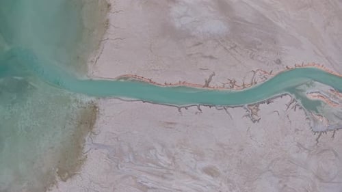Aerial drone view of a turquoise river winding through barren desert terrain with stark contrasts