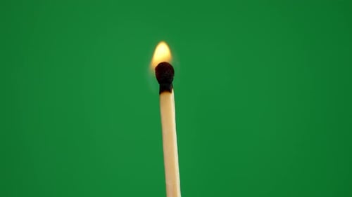 A lit fire match with a green screen background. Flame is weak and soon dies out.