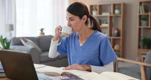 Woman in Scrubs Studying with Books and Laptop