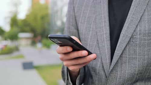 Man in Suit Uses Smart Phone Outdoors