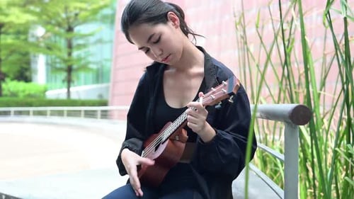Teenage girl with holiday activities, Playing the ukulele in the park
