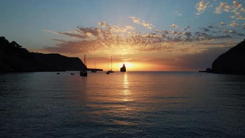 Shot view of boats at sunset at Cala Benirras sea in Ibiza, Spain