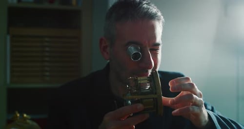 Slow motion close up of a professional watchmaker repairer working on a vintage mechanism clock in