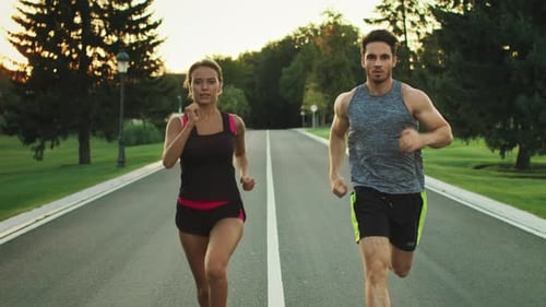 Sport People Running in Park Together. Young Couple Jogging at Outdoor Workout
