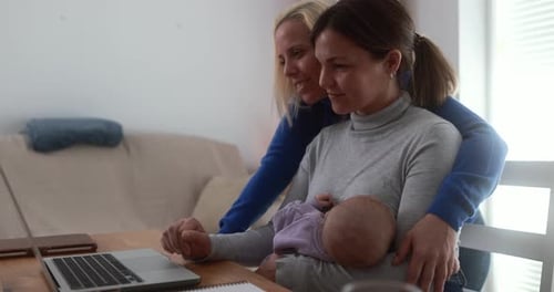 Loving Women with Baby at Desk Using Laptop