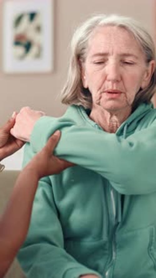 Senior Woman Assisted with Gentle Arm Exercises at Home