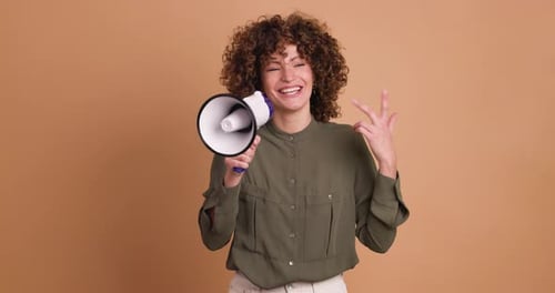 Excited Young Woman Screaming on Loudspeaker in Beige Studio