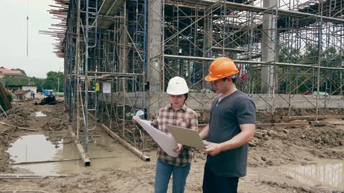Construction manager and engineer discussing and checking plans on construction site.