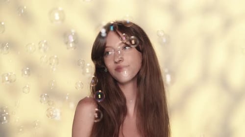 Beautiful Young Girl Playing with Soap Bubbles and Smiling Happily Looking at the Camera