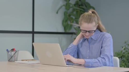 Young Woman with Neck Pain Typing at Desk