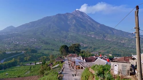 Luftaufnahme des schönen Dorfes mit Blick auf den aktiven Vulkan Merapi, der Rauch abgibt. Wunderschöne Szene