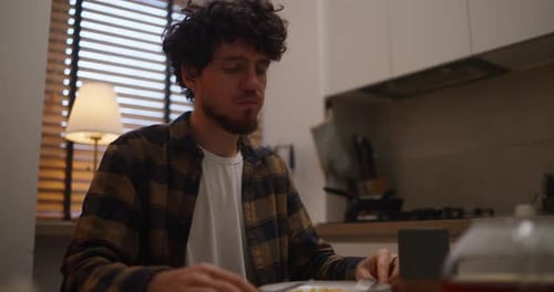 Man Eating and Drinking at Table in Kitchen