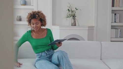 Woman Relaxes on Couch Using Tablet at Home