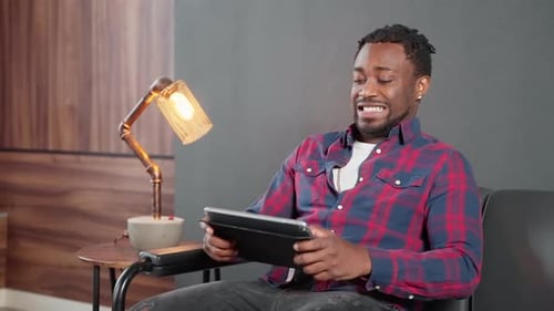 Hombre africano jugando a un videojuego en una aplicación en una tableta: Retrato de adicción a Internet y entretenimiento
