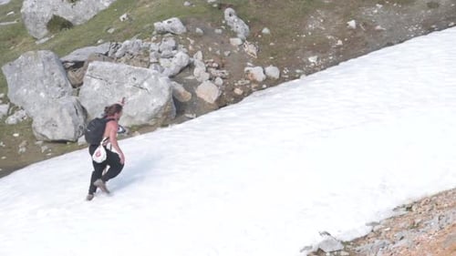 Long Haired Adult Man with a Stick Having Fun in a Snowed Mountain