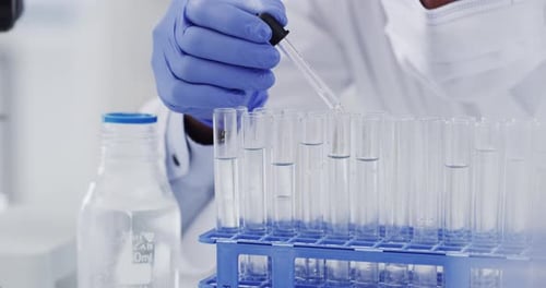 Scientist Adding Liquid to Test Tubes in Lab