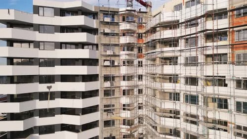 Progreso de la construcción de un edificio residencial moderno con andamios en una zona urbana bulliciosa