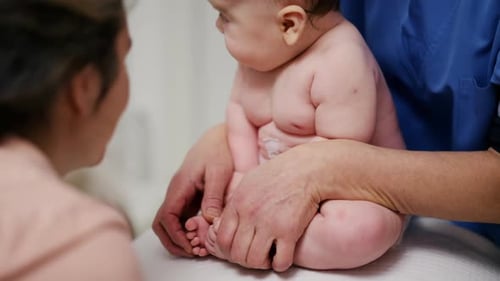 Baby Receives Exam by Adult in Medical Setting