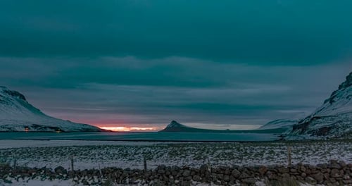 time lapse of rising rose sun in bay with mountains and clouds in iceland